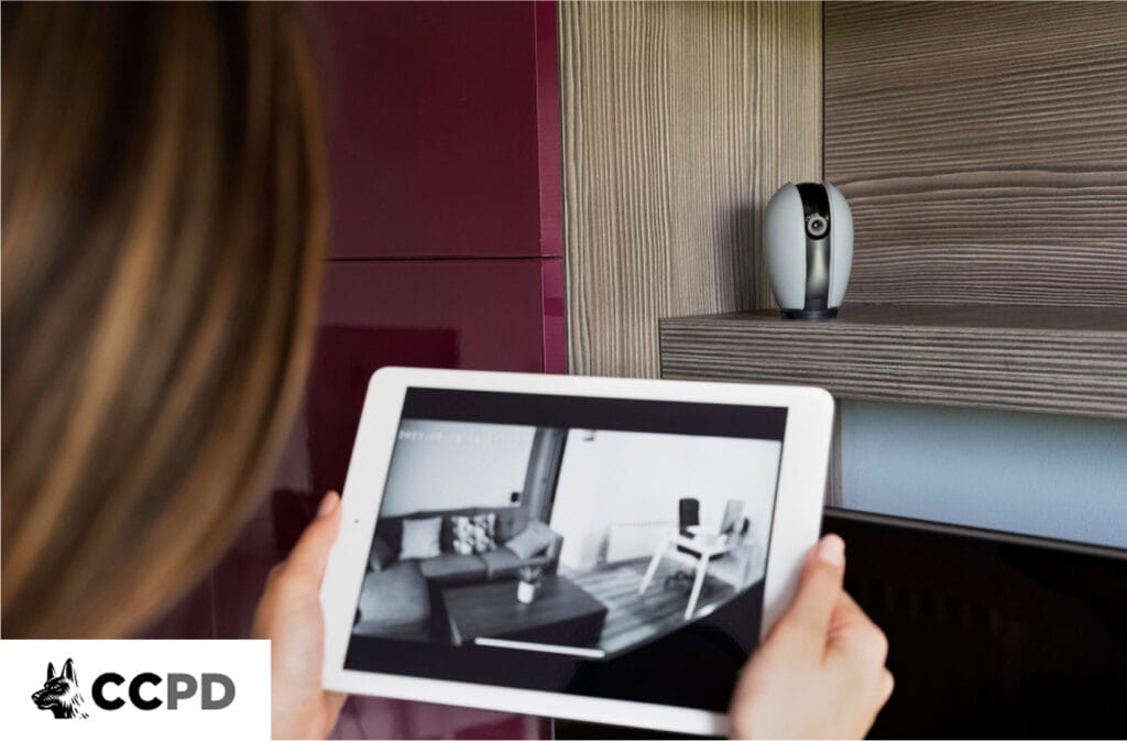 Person remotely monitoring a home security camera feed on a tablet, highlighting the passive and delayed response of electronic systems.